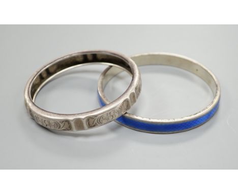 A 1920's silver and blue enamel bangle and an engraved white metal bangle.