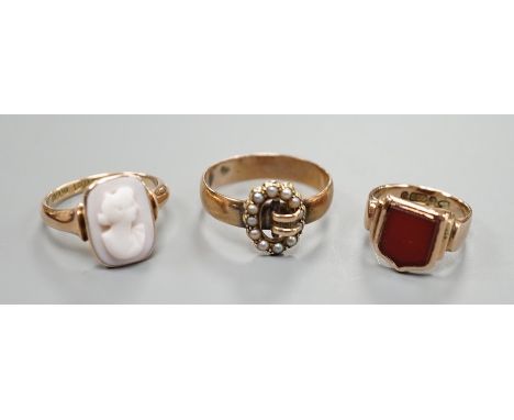 A late Victorian 9ct gold and carnelian set signet ring, size G and tow later 9ct rings including seed pearl buckle and cameo