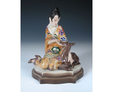 A rare Goldscheider model of an Oriental lady feeding a fawn designed by Marcel Goldscheider, she kneels with the animal to h