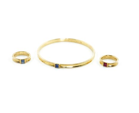 A TIFFANY AND CO GOLD BANGLE AND TWO GOLD RINGS (3)The circular bangle of ridged design, mounted with two baguette sapphires,