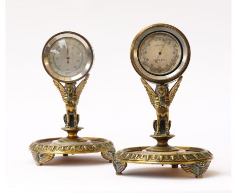 OF EYGPTOMANIA INTEREST: A PAIR OF GILT-BRASS AND ONYX MOUNTED WINGED SPHNIX DESK STANDS FITTED WITH A THERMOMETER AND BAROME