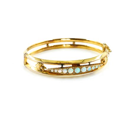 A 9CT GOLD AND OPAL OVAL HINGED BANGLEThe front mounted with a row of eleven graduated opals with diamond points at intervals