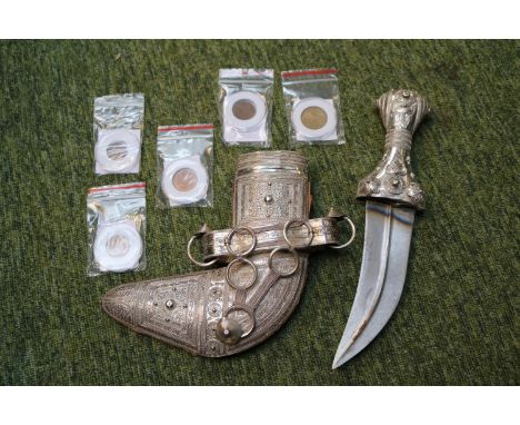 A Yemeni silver mounted jambiya dagger, Curved blade with central ridge, the hilt and scabbard profusely applied with scrolls