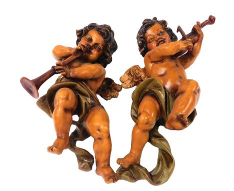 A pair of Continental painted wooden figures of cherubs, each playing a musical instrument, 52cm high. 