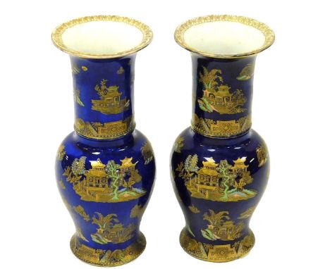 A pair of early 20thC Carltonware Kang Hsi pottery vases, gilt and enamel decorated with a Chinese landscape, against a powde