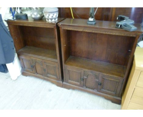 A pair of modern oak Old Charm style bookcases, each having a height adjustable shelf, over a pair of panelled doors, raised 