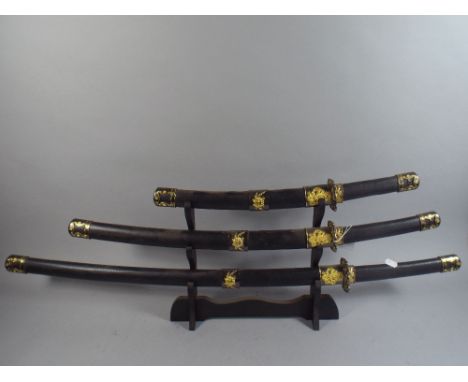 A Modern Reproduction Set of Three Reproduction Japanese Katanas on Stand. 