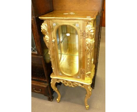 A MODERN PETITE GILT CABINET THE SHAPED TOP OVER THREE GLAZED SIDES, MIRROR BACK, SINGLE GLASS SHELF, LADY FIGURINE DETAIL TO