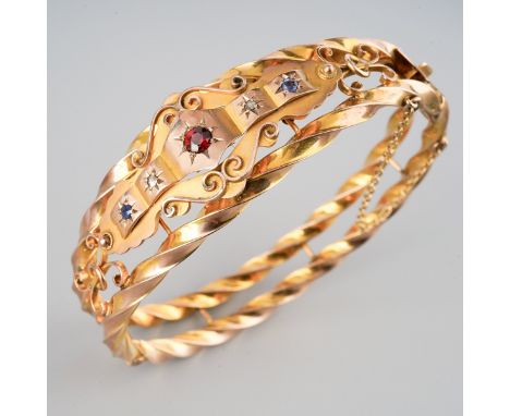 Victorian 9ct gold bangle of twist design with scroll detail, set with sapphires, diamonds and a central garnet, 5.7cm x 4.9c