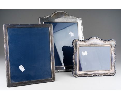 Three Elizabeth II Carrs of Sheffield silver rectangular easel back photograph frames, the largest with serpentine top and ba