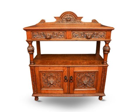 A late Victorian carved oak buffet, the raised back with mask detail, rectangular top with two frieze drawers with carved lio