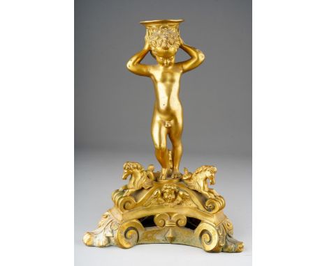 A 18th Century style French gilt metal candlestick, modelled as a putto holding scone aloft on tripod support with hippocampu