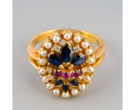 A diamond, ruby and sapphire cluster ring. The oval shape cluster set with three rubies, surrounded by marquise shape sapphir