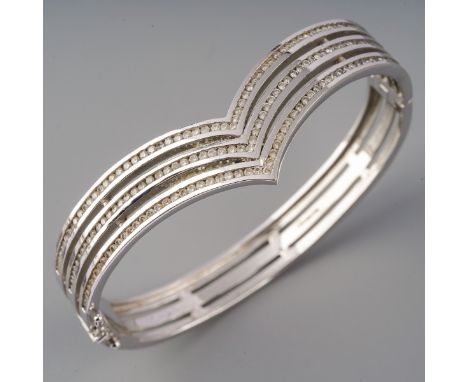 A modern diamond hinged bangle. The front designed as a series of three rows of round brilliant cut diamonds, channel set, to