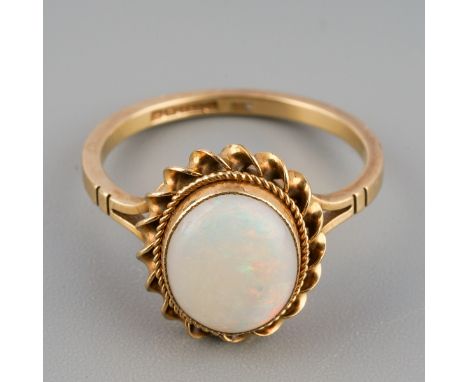 A Retro 1970s 9ct gold opal ring. Set with an oval opal cabochon, within a double rope twist border, to the plain polished ba
