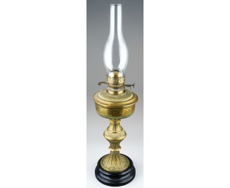 A late Victorian brass based oil lamp, brass reservoir, fluted and reeded decoration, on a black glazed ceramic base, with ch