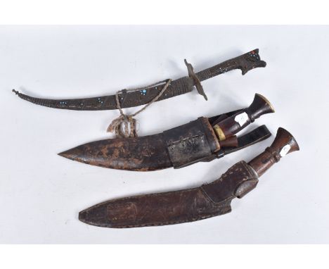 TWO KUKRIS AND AN ORNATE CURVED DAGGER, one kukri is housed in a leather scabbard and the blade has no markings, the handle h