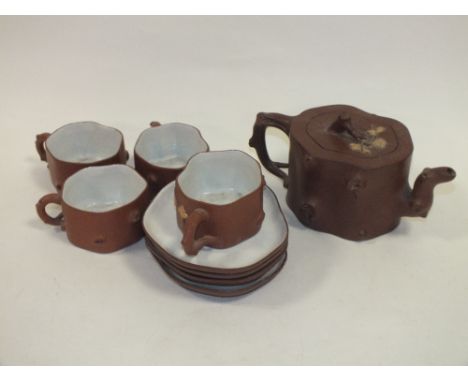 AN ORIENTAL CERAMIC NATURALIST STYLE TEAPOT WITH IMPRESSED MARK TO BASE TOGETHER WITH FOUR CUPS AND SAUCERS