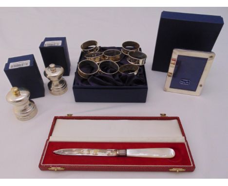 A quantity of hallmarked silver to include eight matching napkin rings, a pair of peppermills, a photograph frame and a lette