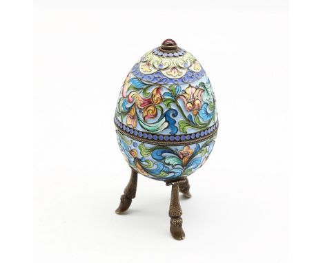 A 20th century Russian silver and enamel egg shaped trinket pot, raised on three hoof legs, decorated in different coloured e