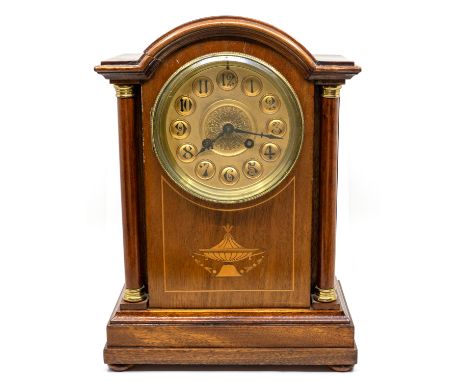 An Edwardian mahogany mantle clock, having domed top with cylindrical column supports, inlaid urn design to front, on four bu
