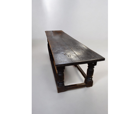 An early 17th century oak refectory type table, the twin planked cleated top raised on a channel moulded frieze, with ring tu