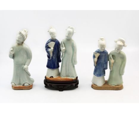 Two similar Chinese porcelain couples, 18th century, he wears a celadon glazed jacket, she a blue jacket, one on oval base, e
