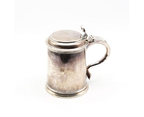 A George I Britannia standard silver tankard, with plain tapering sides and skirted foot, hinged cover with scrolled thumbpie