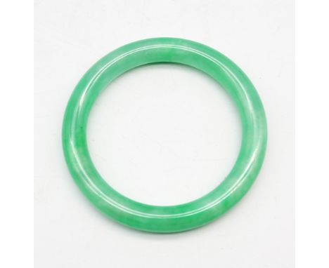 A Chinese jade type bangle, of bright green mottled hue, approx. 8.5cm diameter, 20th century.  Further details: no signs of 