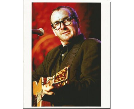 Elvis Costello signed 10 x 8 inch colour photo on stage playing the guitar. His critically acclaimed debut album, My Aim Is T