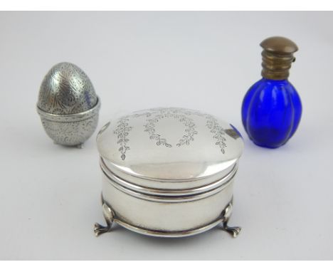 George V  circular engraved silver trinket box, a later egg shaped box and a French blue glass scent bottle. 
