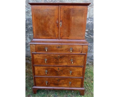 An antique mahogany and cross banded chest on chest, the upper section fitted with a pair of cupboard doors opening to reveal