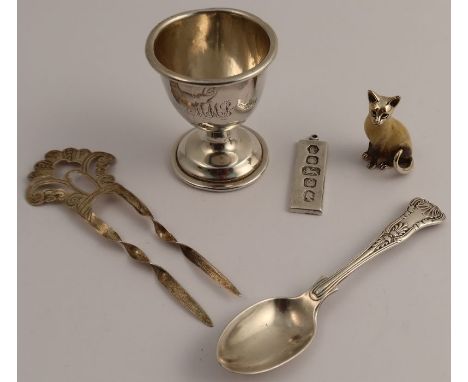 A collection of hallmarked silver, to include an egg cup, an ingot, a coffee spoon, a hair comb and a model of a cat, weight 