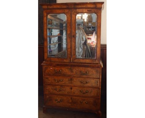 An antique walnut cabinet on chest, the upper section fitted with a pair of mirrored doors, opening to reveal drawers, the ba