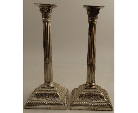 A pair of Victorian silver candlesticks, with Corinthian capitals to the fluted column, raised on square bases decorated with