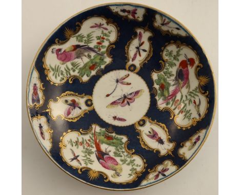 An 18th century Worcester saucer dish, the scale blue ground decorated with reserve panels of insects and fabulous birds, sea