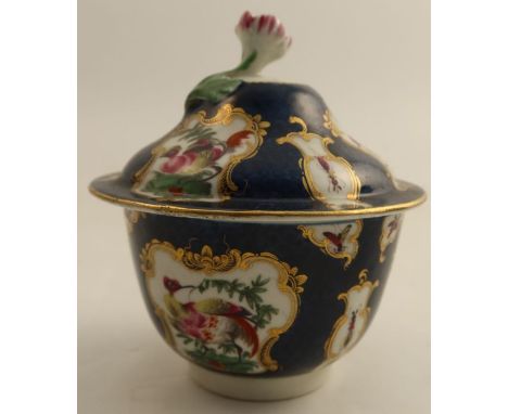 An 18th century Worcester covered sugar bowl, the scale blue ground decorated with reserve panels of insects and fabulous bir