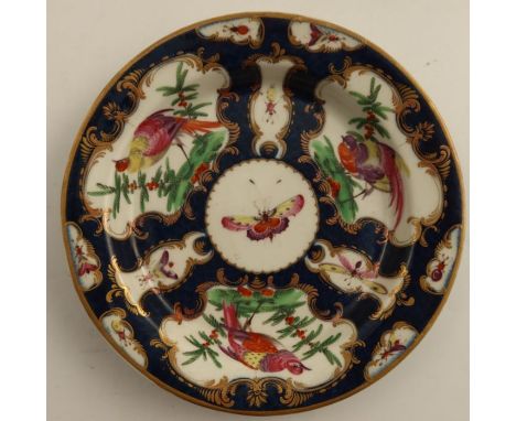 An 18th century Worcester side plate or saucer dish, the scale blue ground decorated with reserve panels of insects and fabul