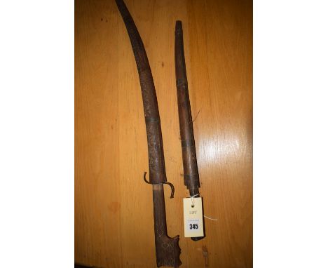 A Middle Eastern ornamental dagger with carved wooden handle, in carved wooden scabbard; a similar dagger with a straighter b