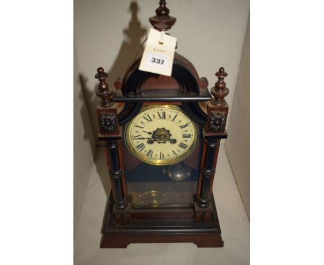 A Victorian style mantel clock in ebonised and mahogany case, with circular cream coloured roman dial.