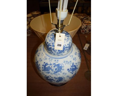 A modern large Oriental blue and white ceramic ginger jar style table lamp, with tapering pleated cream coloured shade.