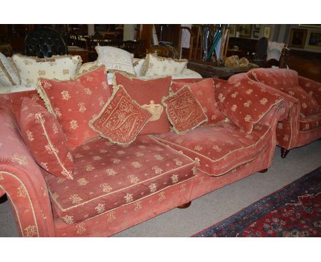 A sofa covered in monogrammed material, fitted loose seat and scatter back cushions; together with a large armchair to match.