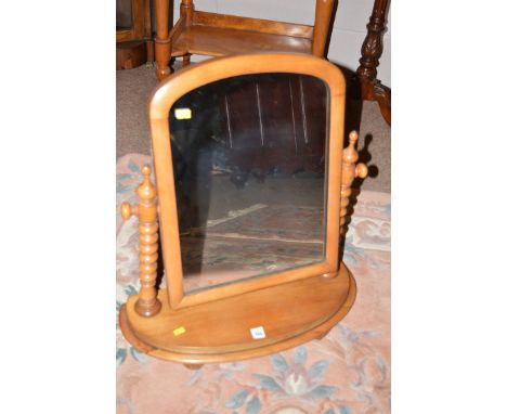 A toilet mirror, the arched mirror plate on bobbin turned supports.
