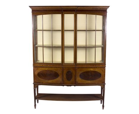 An Edwardian kingwood and mahogany inlaid display cabinet with moulded cornice above two glazed doors, the bow front enclosin