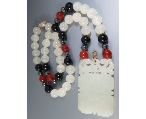 A Carved and Pierced Jade Pendant decorated with twin birds, with Chinese character below and water lily to the other side an