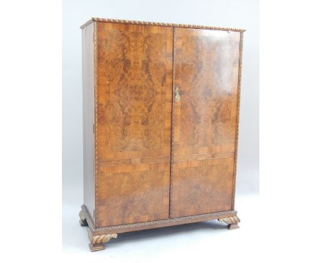 Mid 20th century walnut wardrobe, of compact size, the carved gilt detailed gadrooned cornice above a pair of panel doors enc