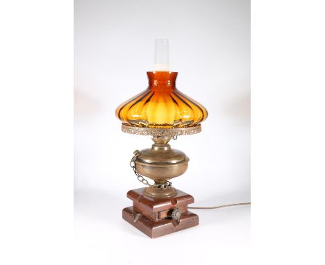 Antique style paraffin lamp converted to an electric table lamp with amber coloured glass shade, raised on wooden base with s