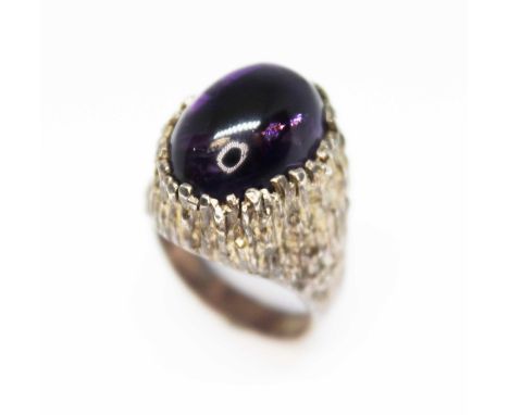A Modernist cast silver ring by Sidney Beddall, set with a large oval amethyst cabochon, sponsor's mark 'PGW', London 1970, g