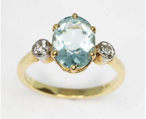 An aquamarine and diamond ring, the central six claw set oval cut stone weighing approx. 1.77ct, mounted above two millegrain