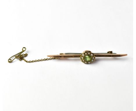 An Edwardian 9ct gold bar brooch with a flower cluster centre comprising cut green stone within a halo of tiny seed pearls, s